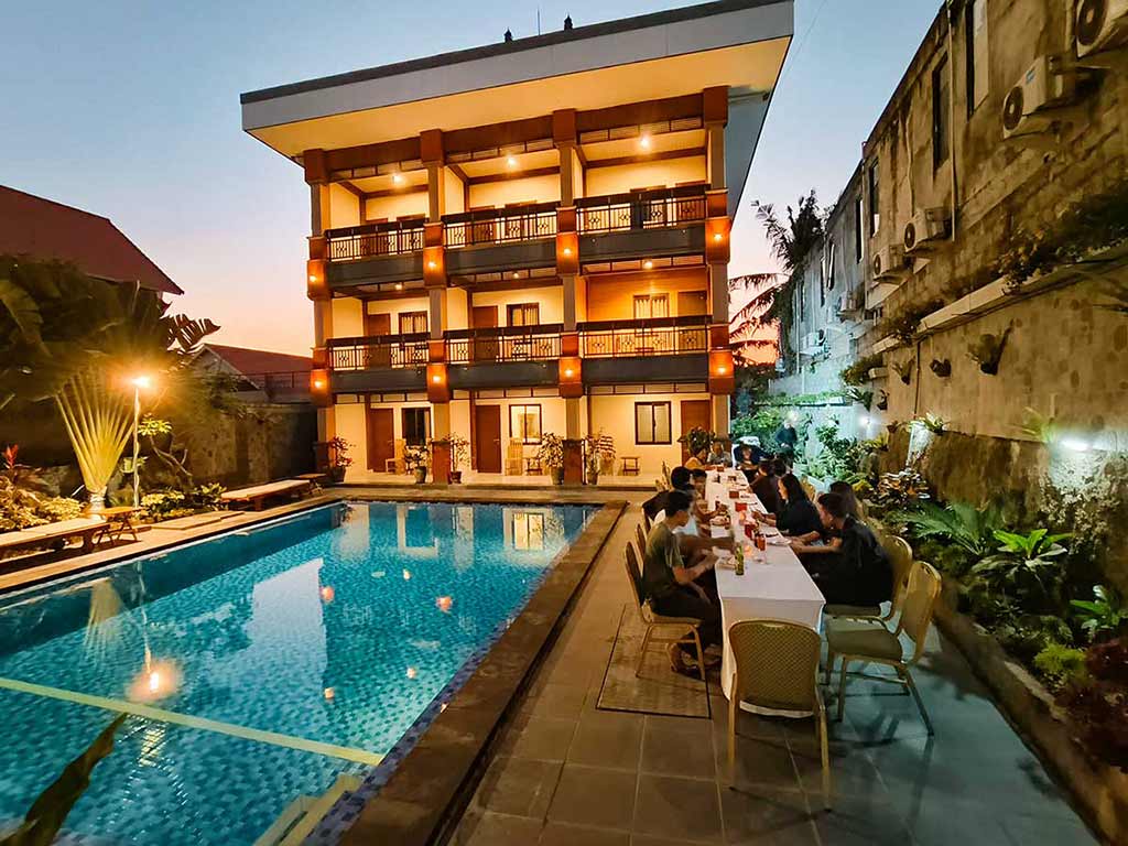Domestic tourists enjoying a romantic dinner together by the illuminated swimming pool at Tunjung Boutique Resort in the evening.