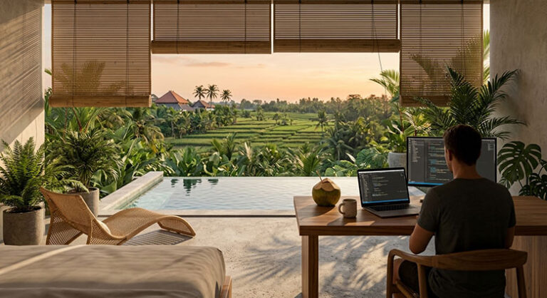 A remote worker sits at a wooden desk with a laptop overlooking a private pool and green rice fields in Bali.