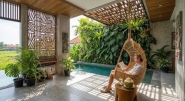 A man reads a book in a hanging rattan chair by a private pool in a Tumbak Bayuh villa.