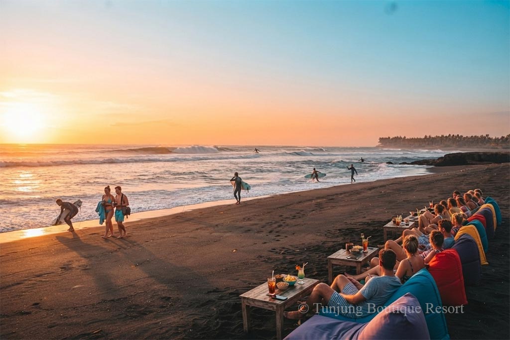 Tourists relaxing on colorful beanbags watching surfers under a bright sunset, offering a quiet stay in Canggu vibe near Pererenan Beach.