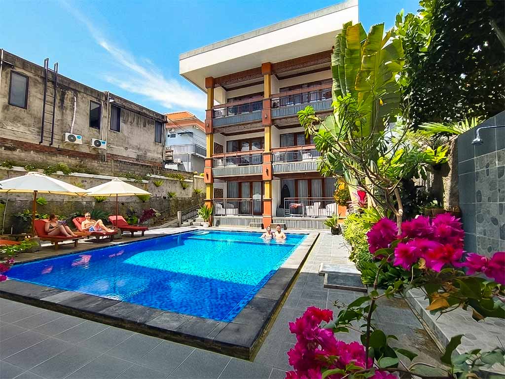 Guests relaxing by the tranquil swimming pool at The Tunjung Boutique Resort for a peaceful and quiet stay in Canggu.