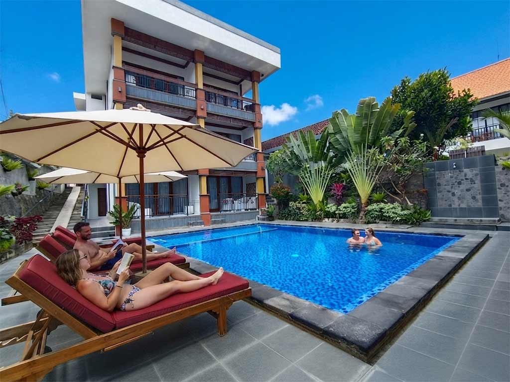 Guests relaxing around the sunlit swimming pool at The Tunjung Boutique Resort during a peaceful weekend in Canggu.