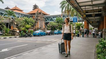 a woman with a suitcase and backpack walks through the arrival area of Ngurah Rai Airport in Bali, Indonesia